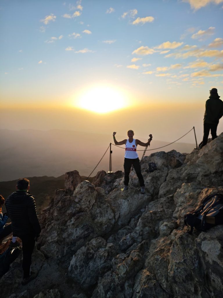 Sunrise on the summit of Teide at 3,715 m, a hiker with raised arms above a sea of clouds