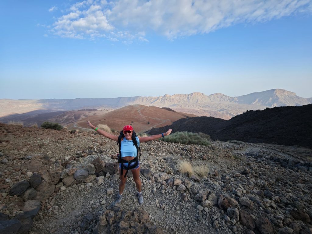 Hiker with arms spread wide on the trail to the Altavista refuge, panorama of Teide National Park
